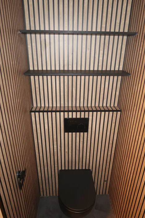 Zwart hangtoilet tegen een wand met houten lamellen