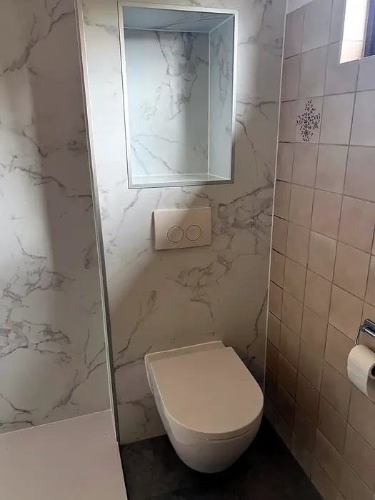 Hangtoilet in witte marmerlook wand met inbouwnis