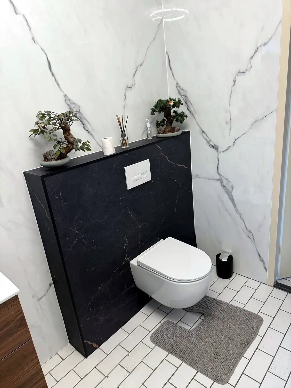 Zwevend toilet met zwarte marmerlook voorzetwand en witte marmerlook wandpanelen