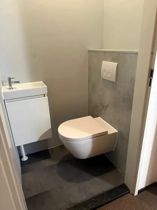 Toiletruimte met hangtoilet, betonlook voorzetwand en fonteintje