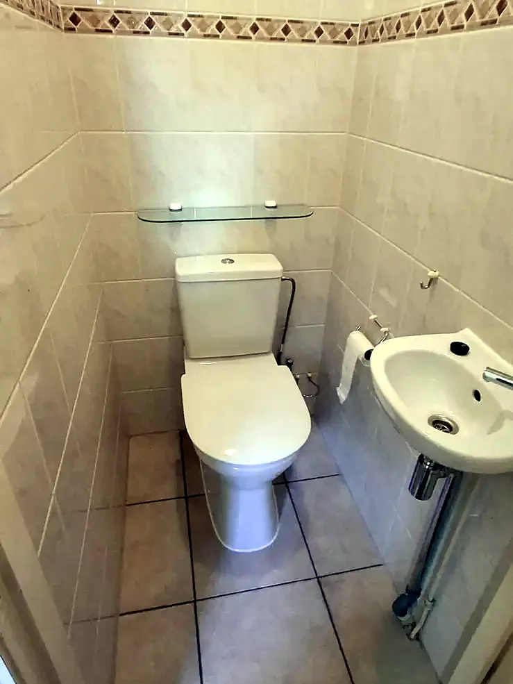 Smalle toiletruimte met oude tegels en fonteintje vóór de renovatie